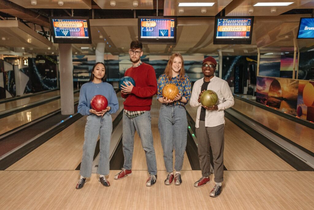 Group posing with bowling balls in front of the lanes